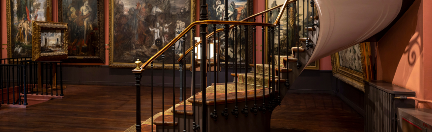 Vue du deuxième étage du musée avec un bout de l'escalier et les oeuvres au mur