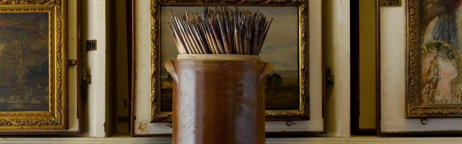 pot de pinceaux de peintures avec des tableaux en arrière-plan